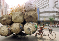 A CHINESE MAN PULLS A CART PACKED HIGH WITH BAGS OF PLASTIC CONTAINERS
IN SHANGHAI.